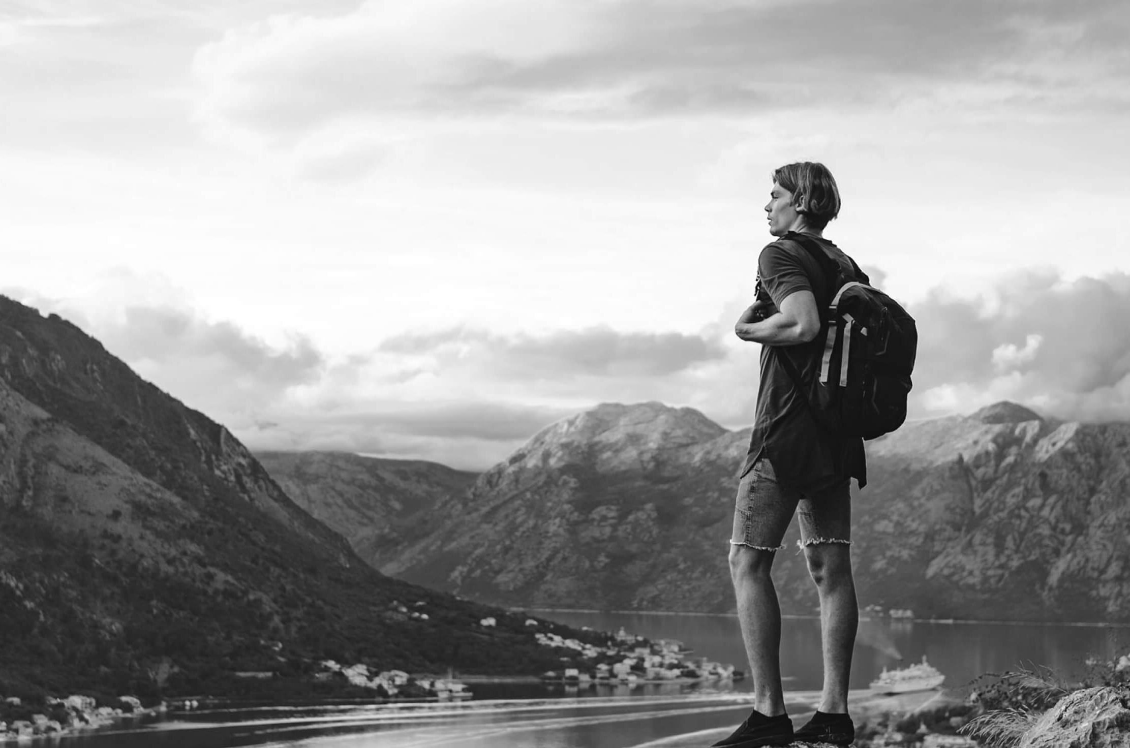 Hiker looking out over mountains and a coastal town